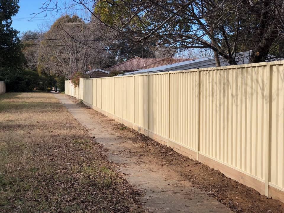 A long white fence along a sidewalk next to a house.