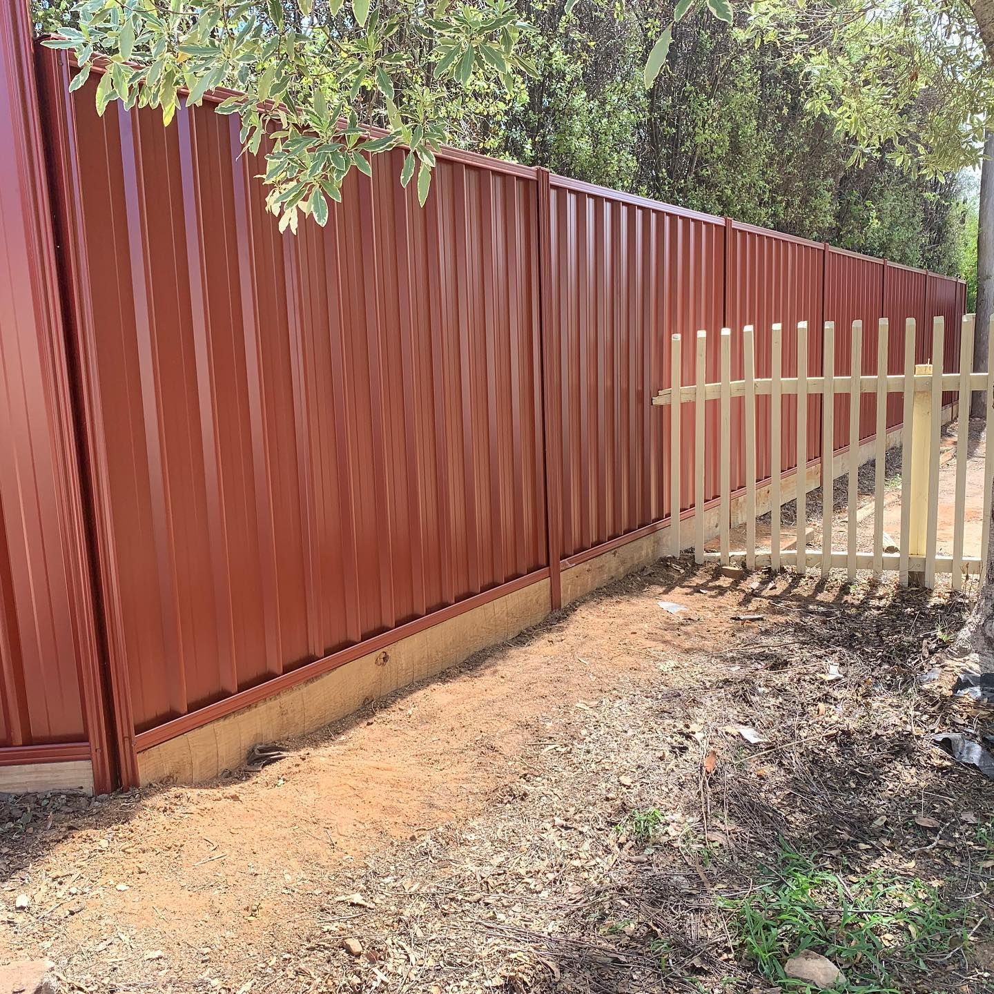 A red fence with a white picket fence next to it.