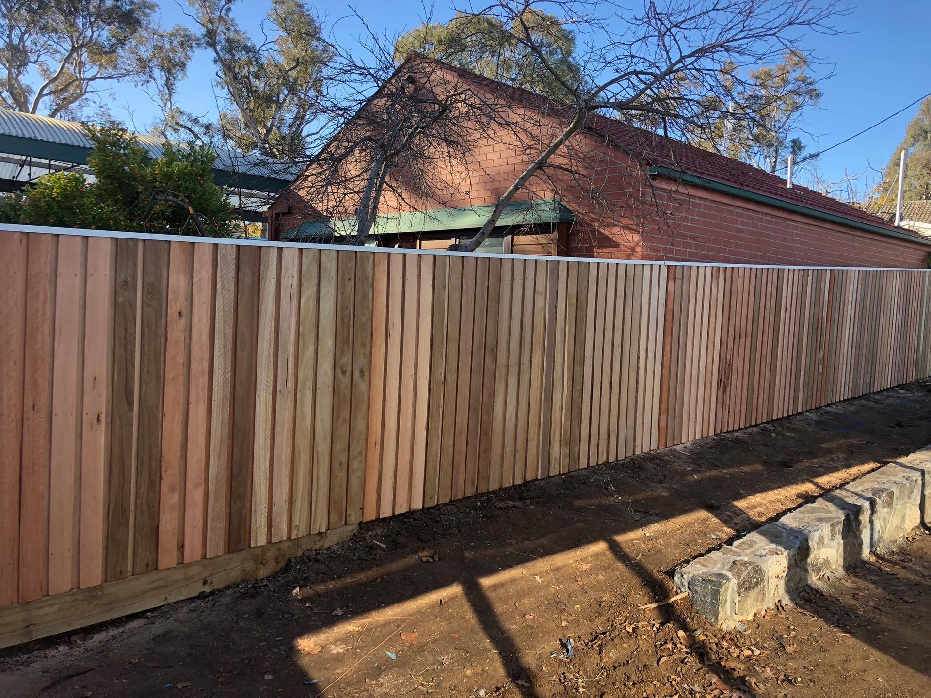 A wooden fence is sitting in front of a brick house.