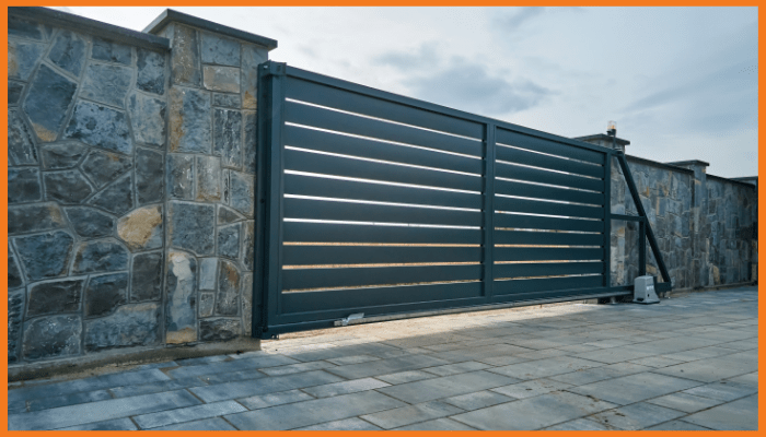 A black sliding gate is sitting in front of a stone wall.