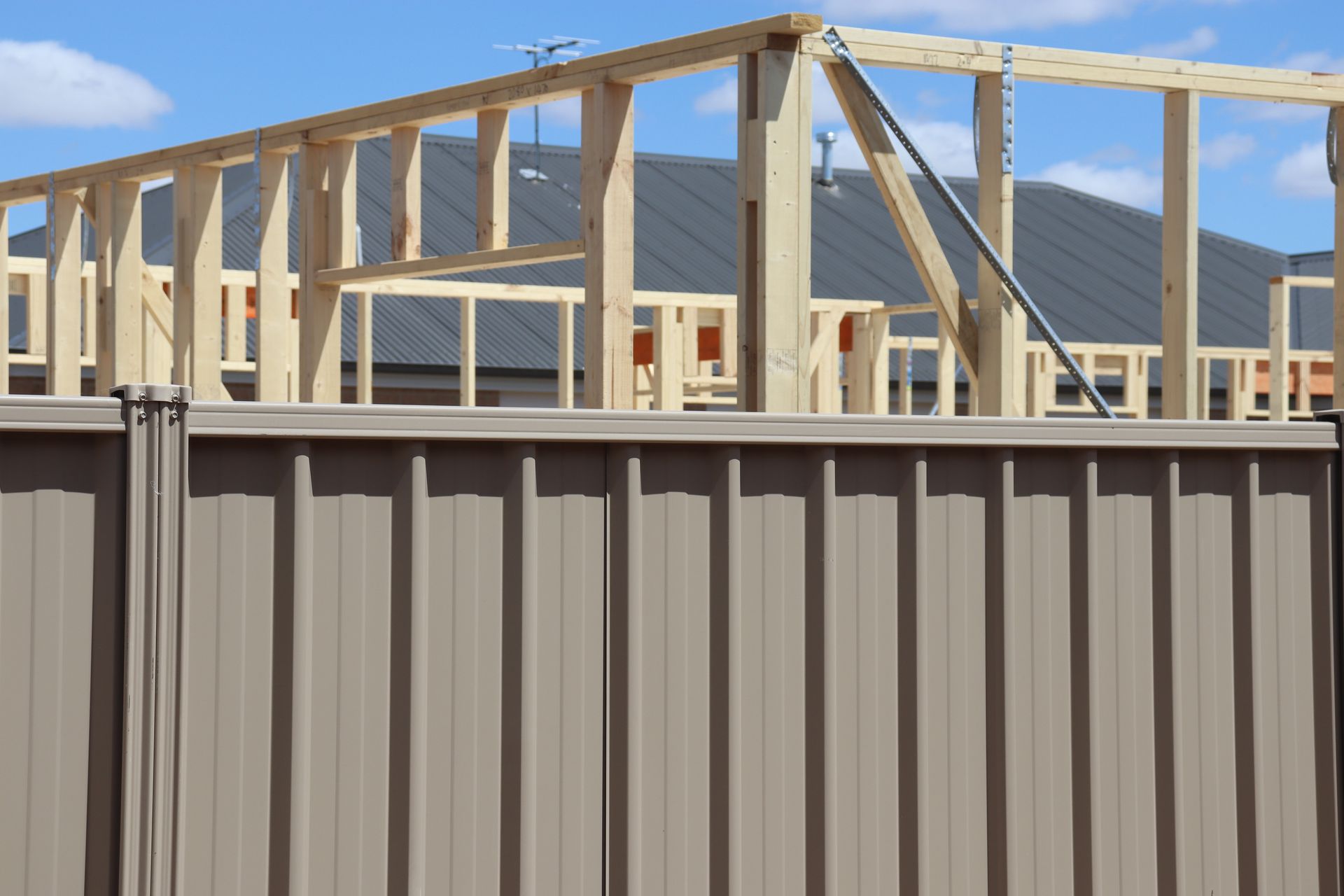 A house is being built with a fence in the foreground.