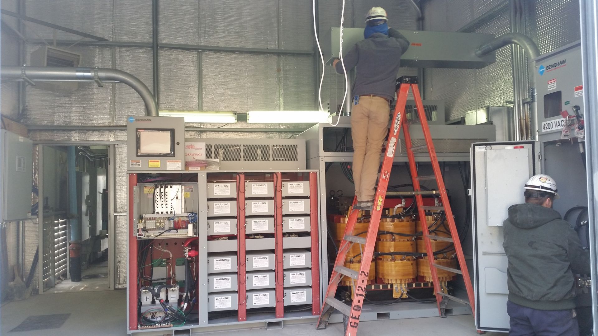 A man in a hard hat is holding a light bulb in a living room.