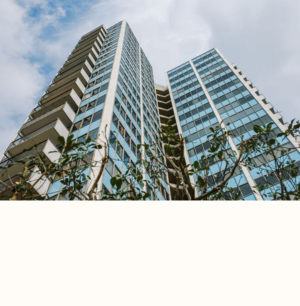 Looking up at a tall building with a tree in front of it
