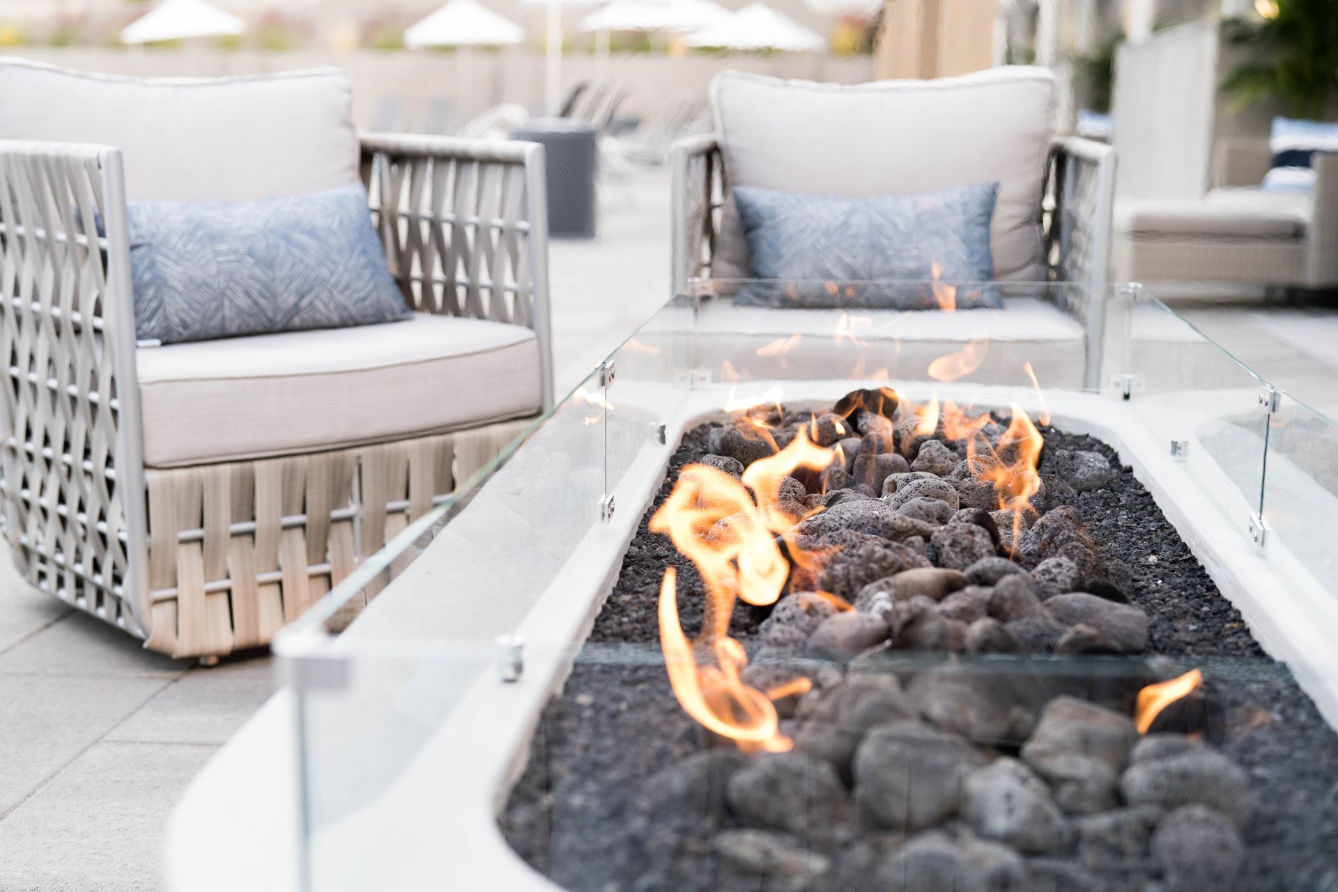 a fire pit sits between two chairs on a patio