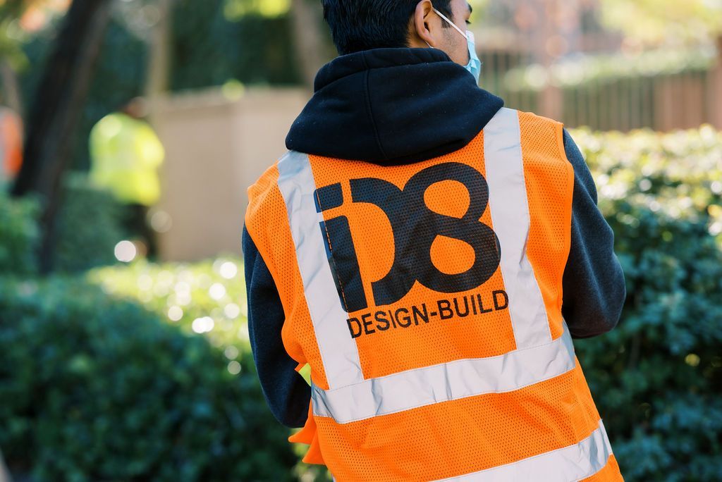a man wearing an orange vest that says id8 design-build
