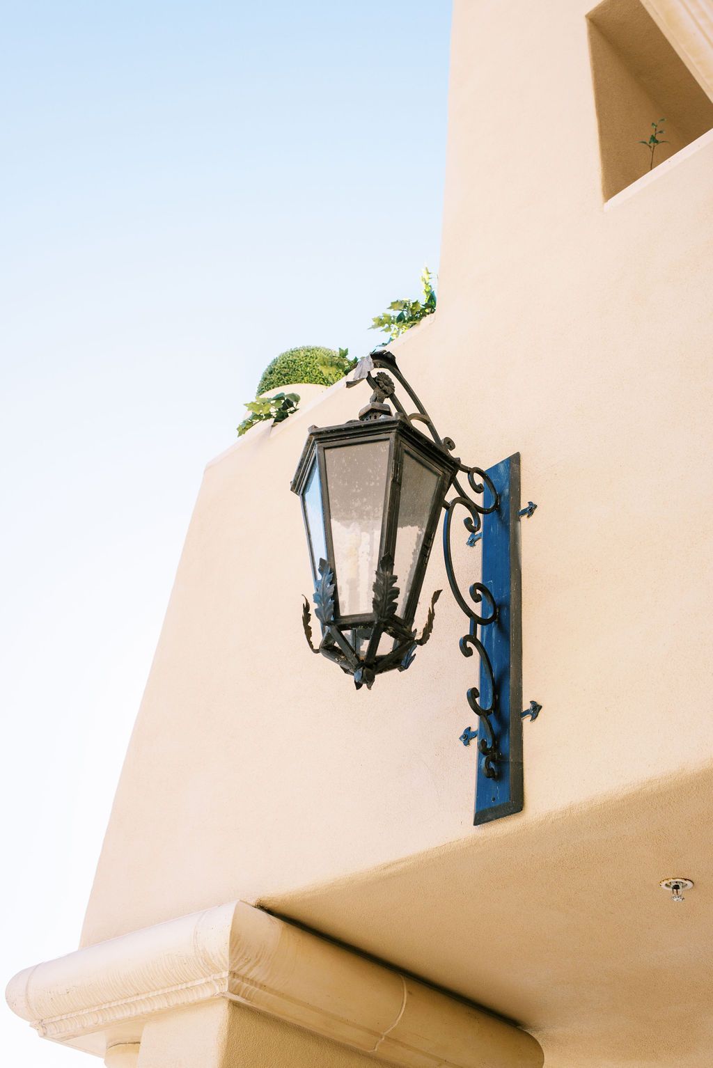a wrought iron lantern hangs on the side of a building