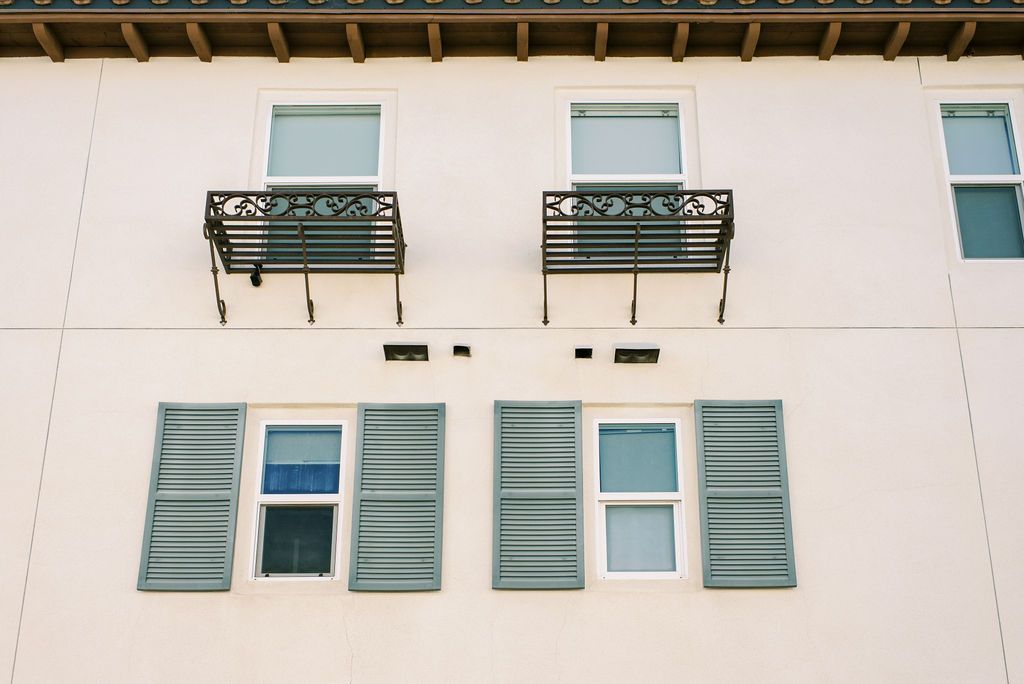a white building with green shutters and a balcony