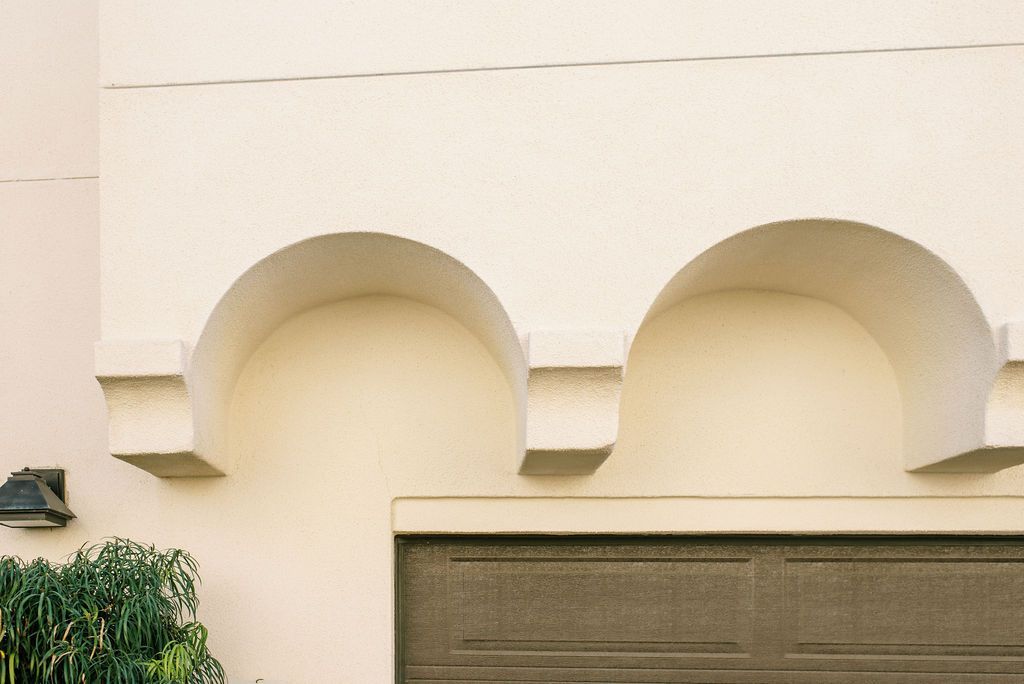 a white building with arches and a brown garage door