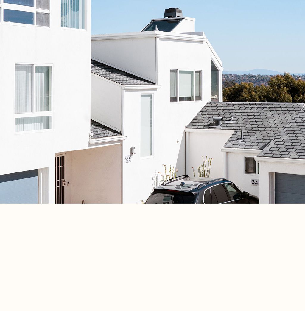 A white house with a car parked in front of it.