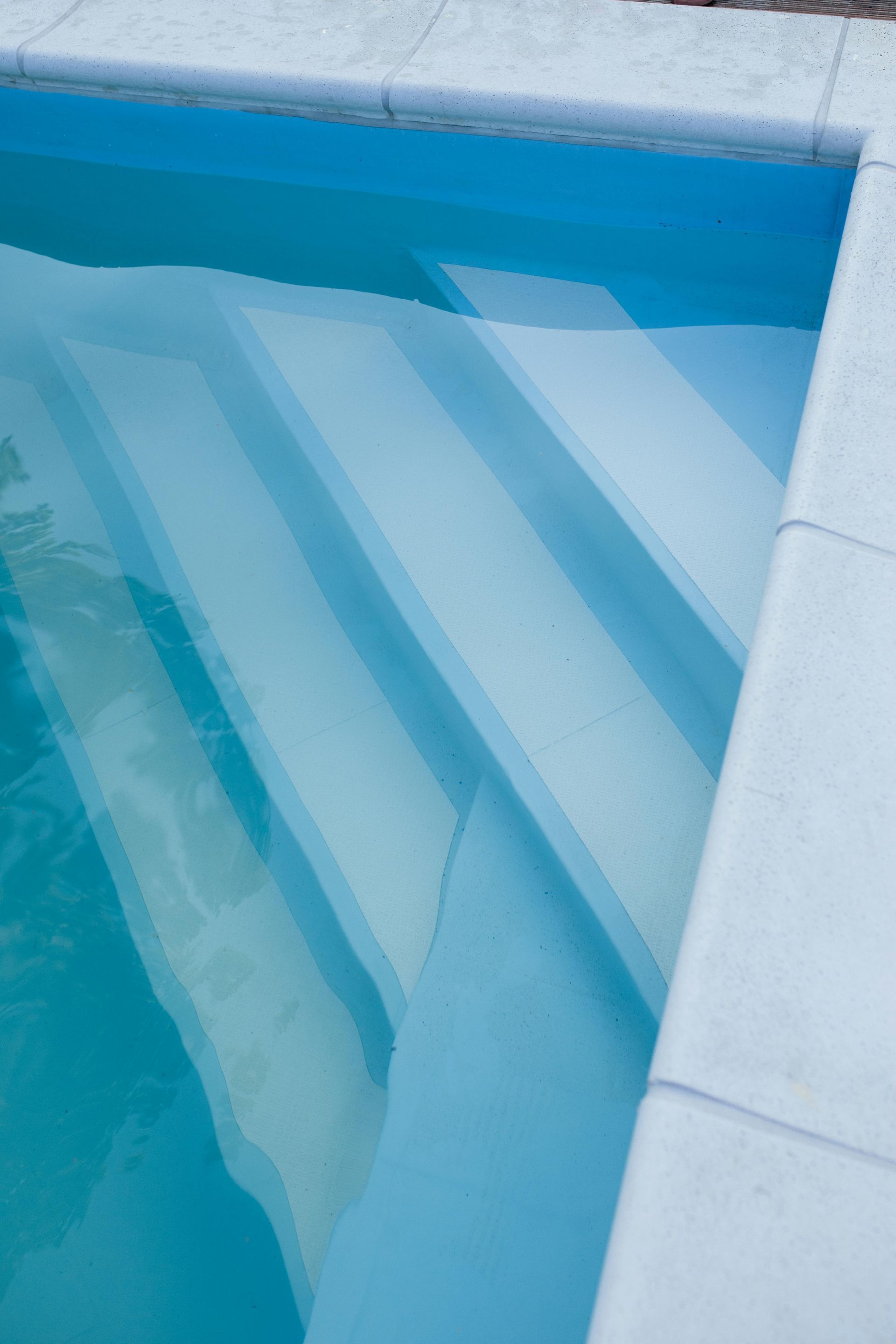Pool steps submerged in clear blue water with white tile edging.