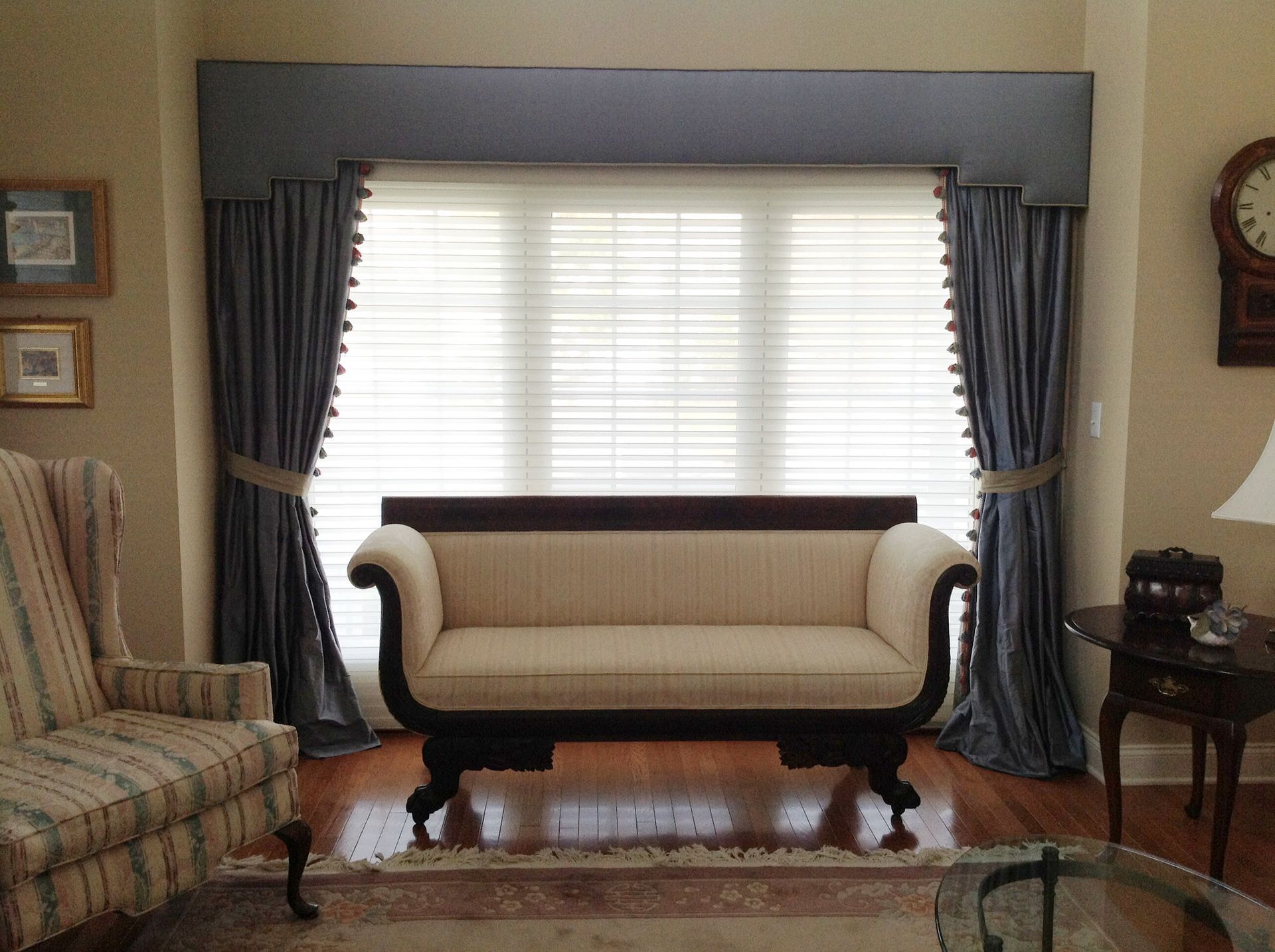 Living room with a blue curtained window, cream sofa, chair, and side table.