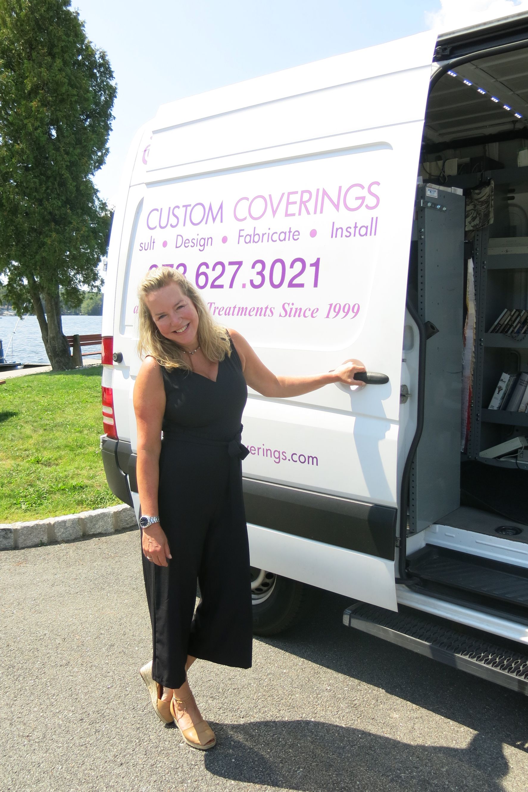 A woman is standing next to a white van with the door open.