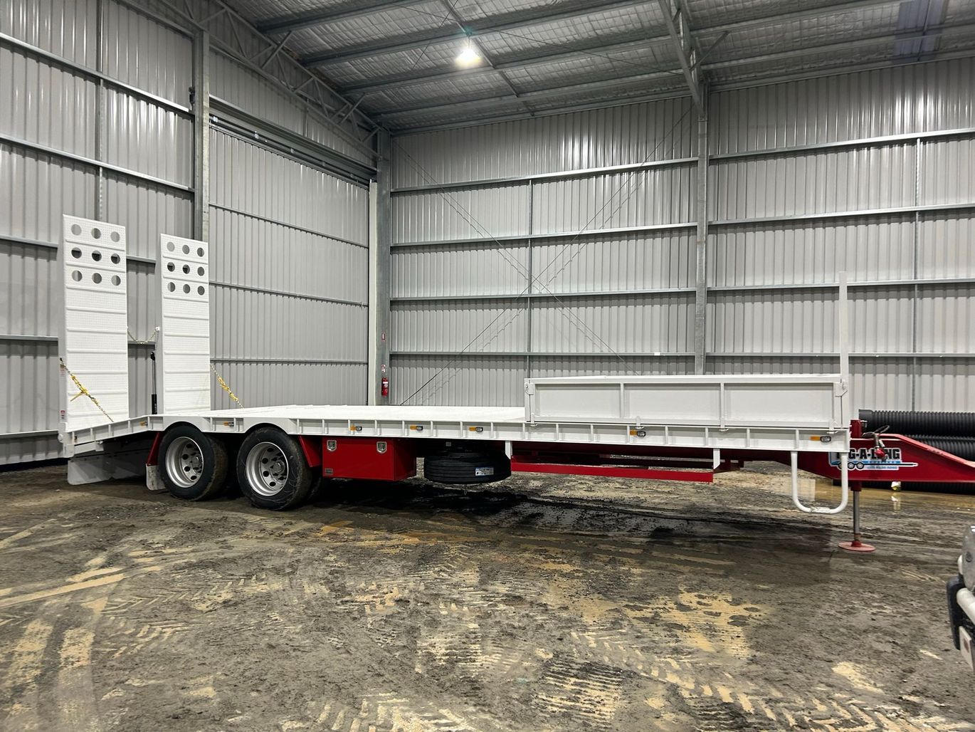 A flatbed trailer is parked in a warehouse.