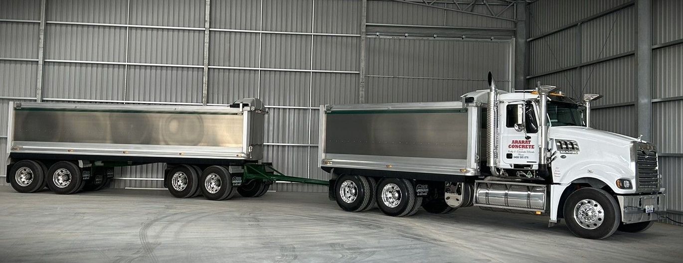 A dump truck and trailer are parked in a warehouse.
