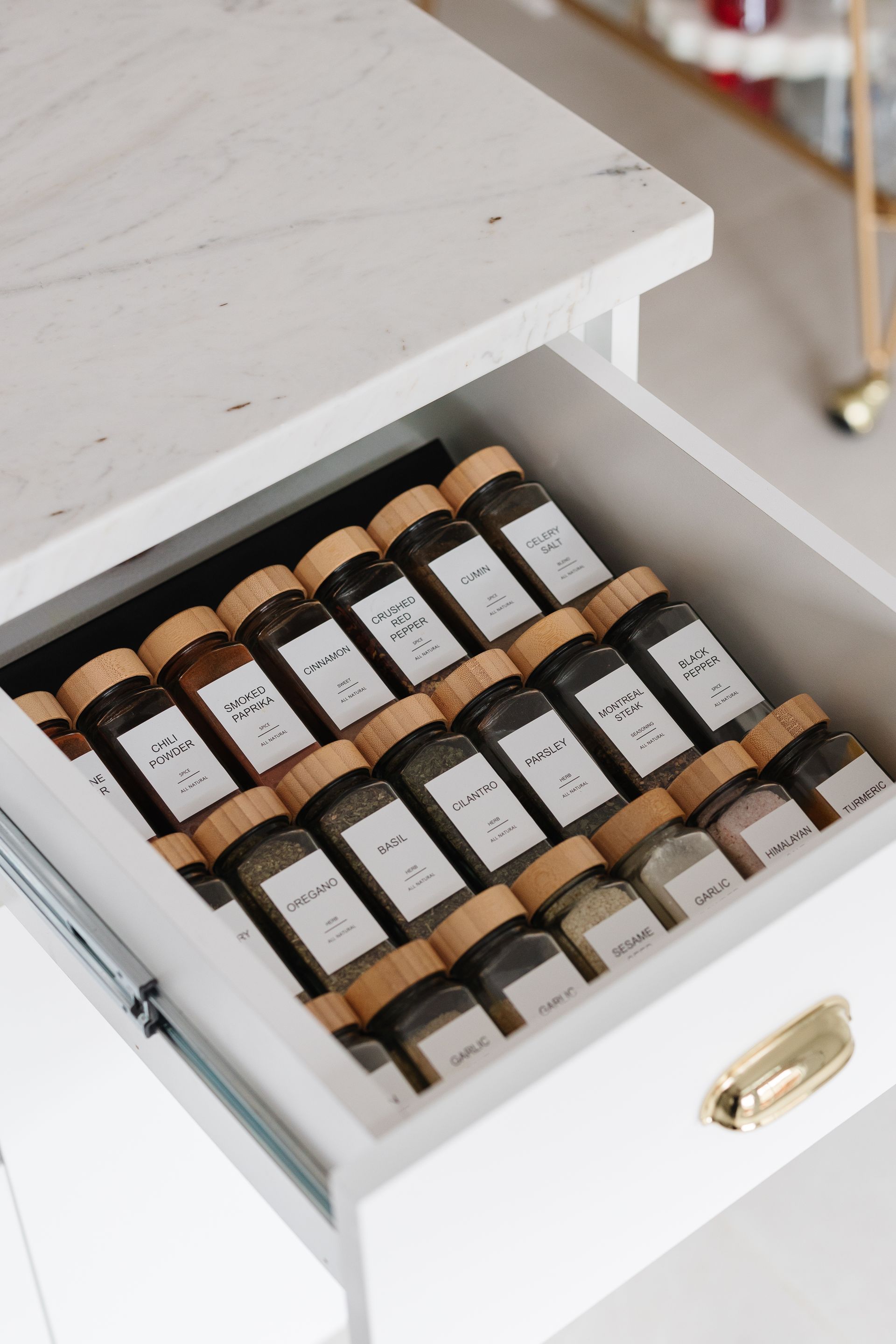 White drawer with neatly arranged spice jars, each labeled.