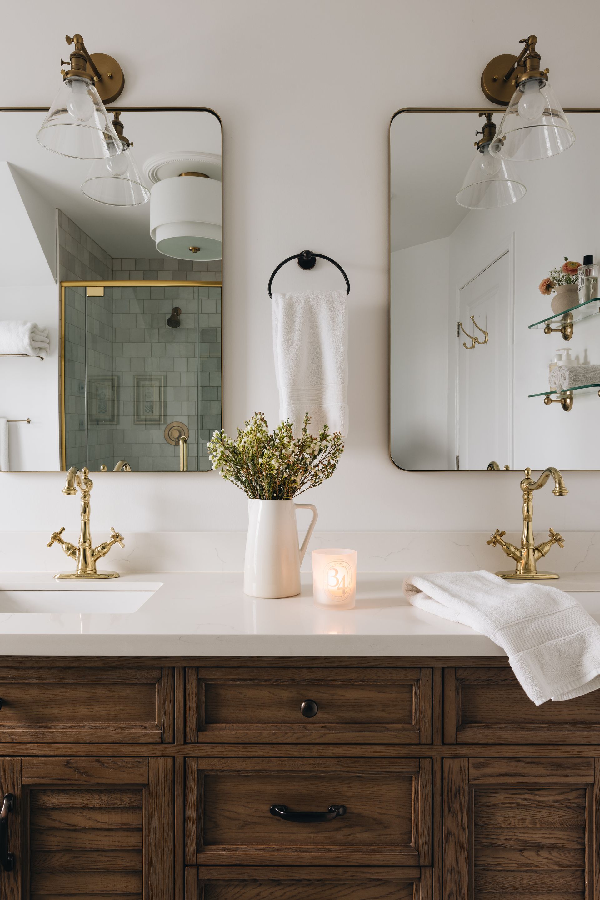 Bathroom with two framed mirrors, gold fixtures, and a wooden vanity.