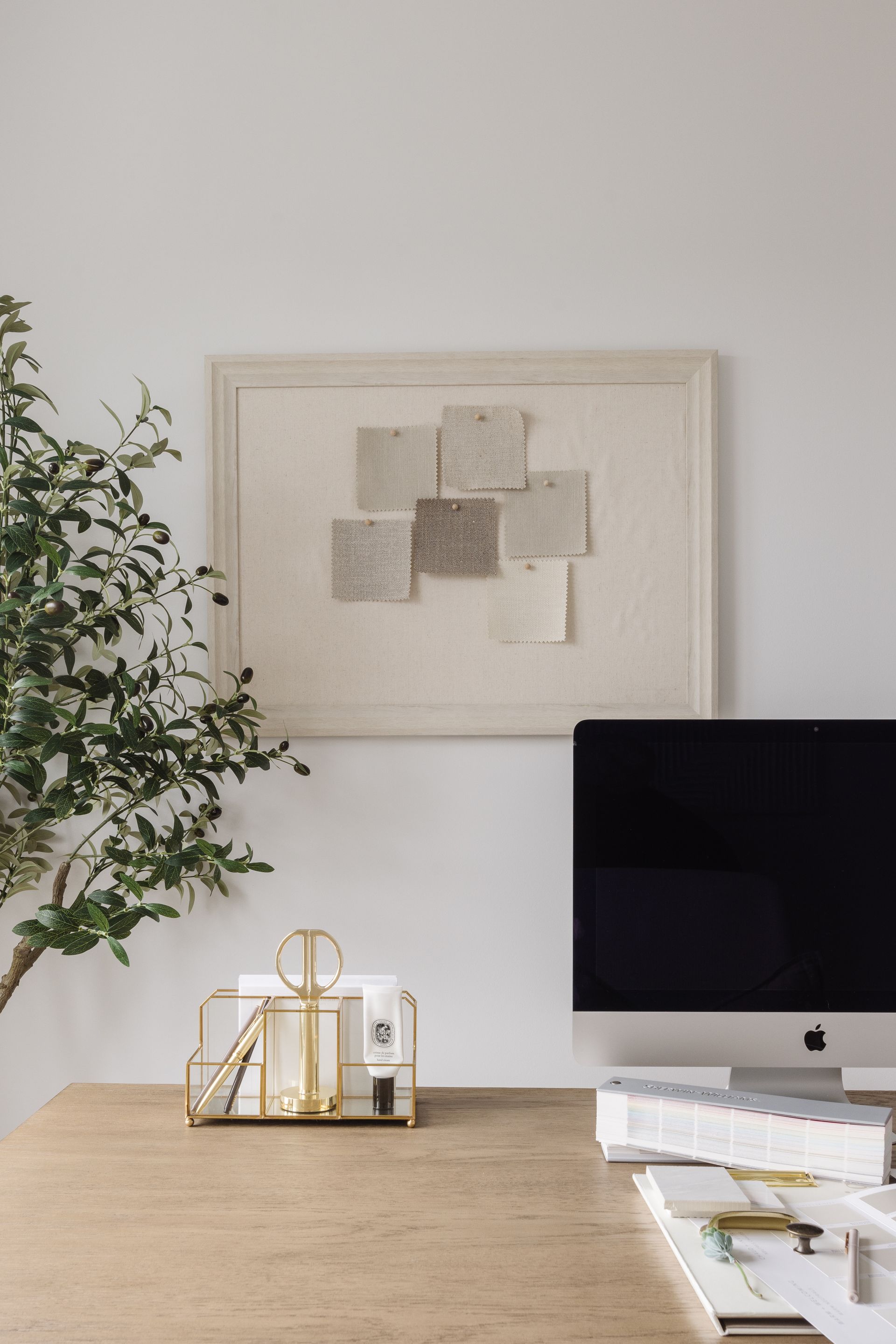 Desk with computer, art, and office supplies; neutral tones.