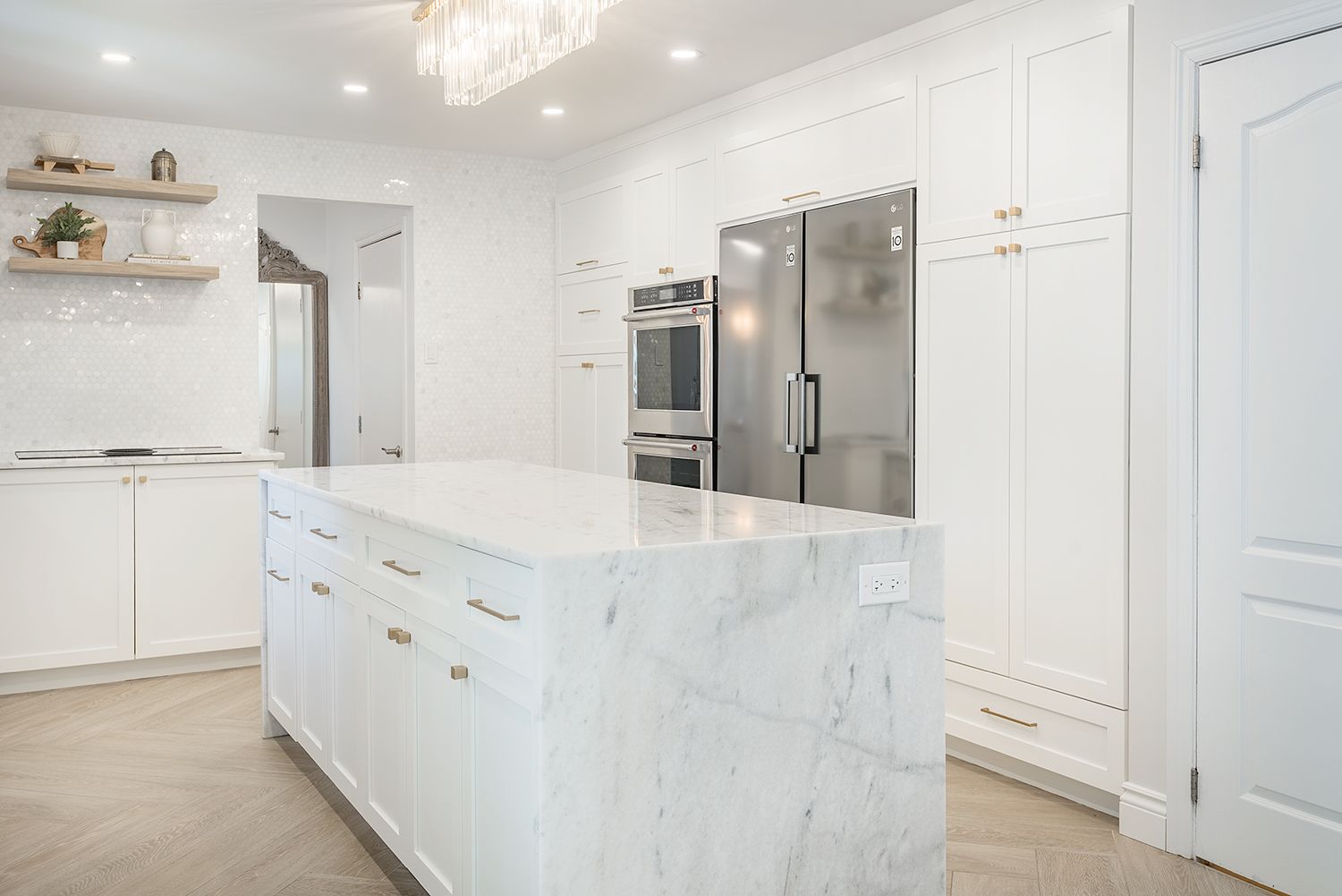 White kitchen with marble island, stainless steel appliances, and wood floors.