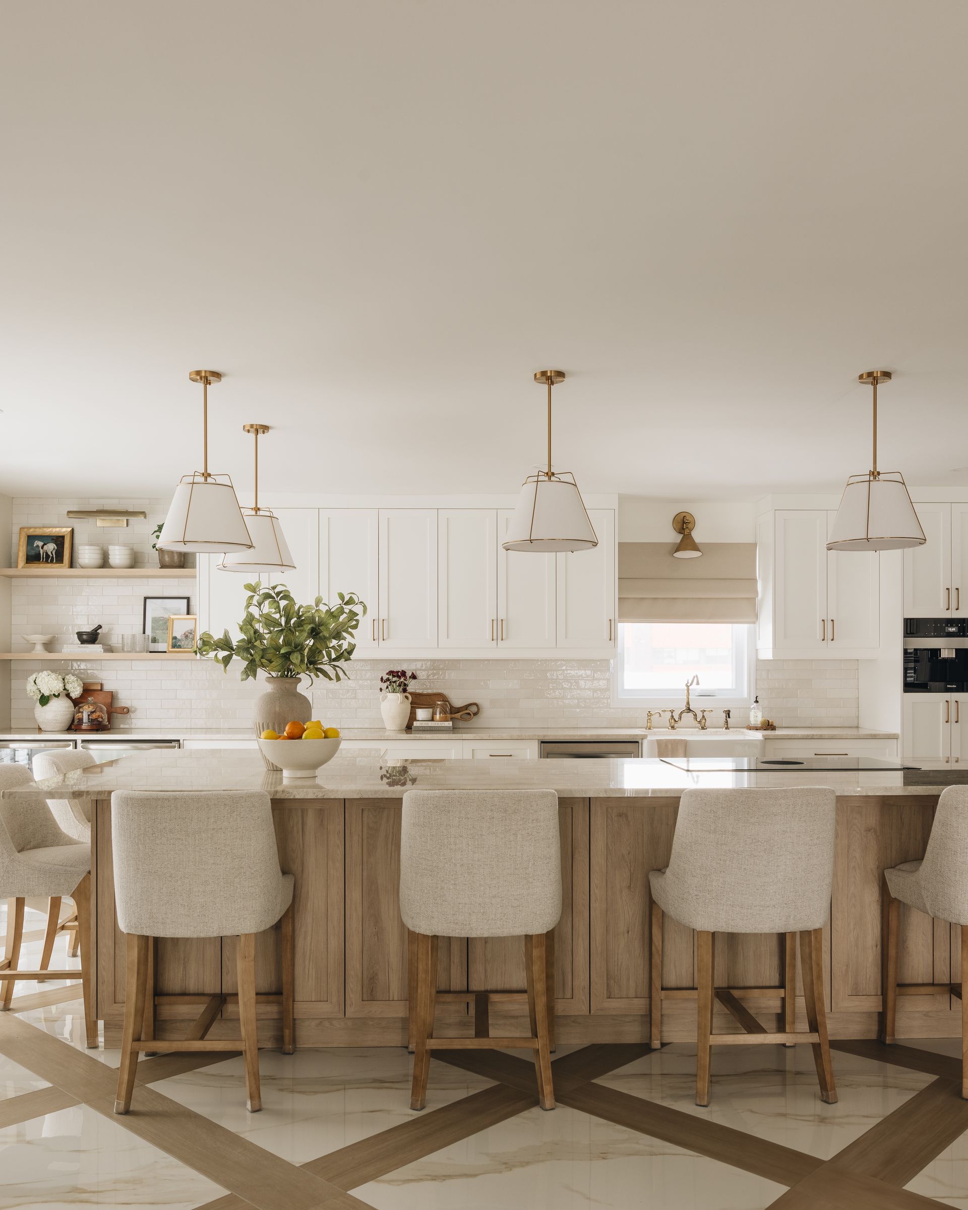 Light-filled kitchen with a wooden island, white cabinets, and pendant lights above the bar stools.
