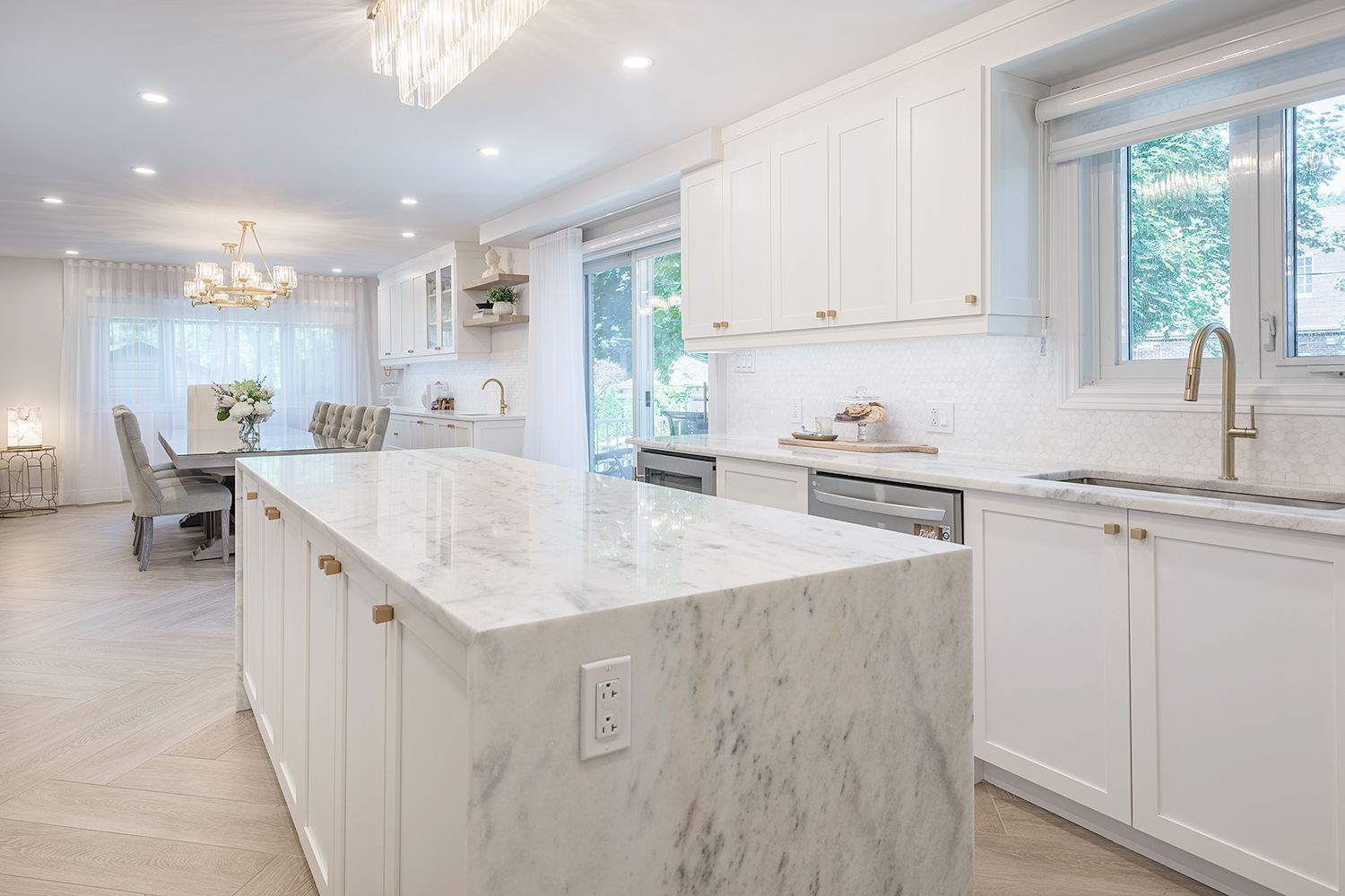 Bright white kitchen with marble countertops, island, and gold hardware.