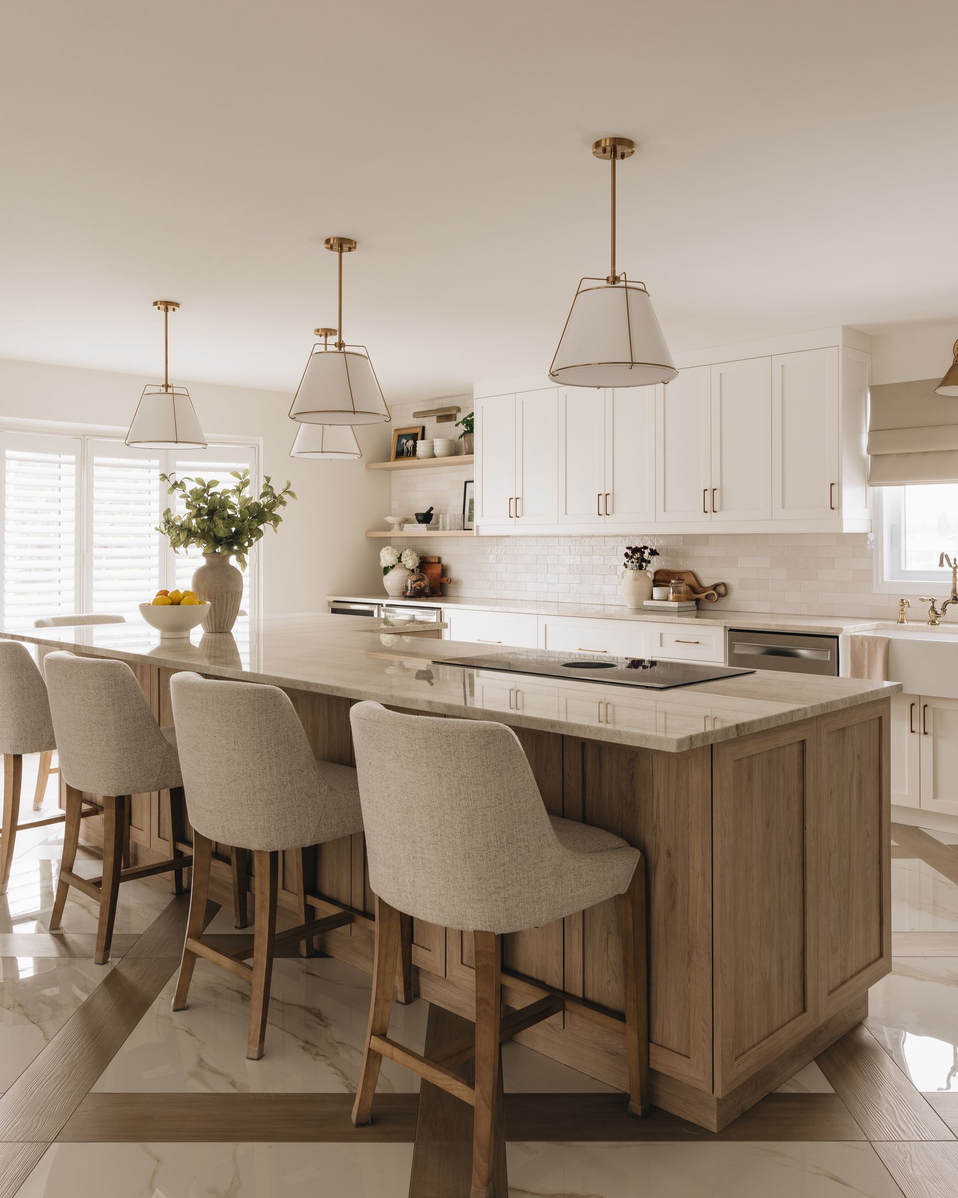 Elegant kitchen with a wooden island, white cabinets, and pendant lights. Bar stools with light fabric.