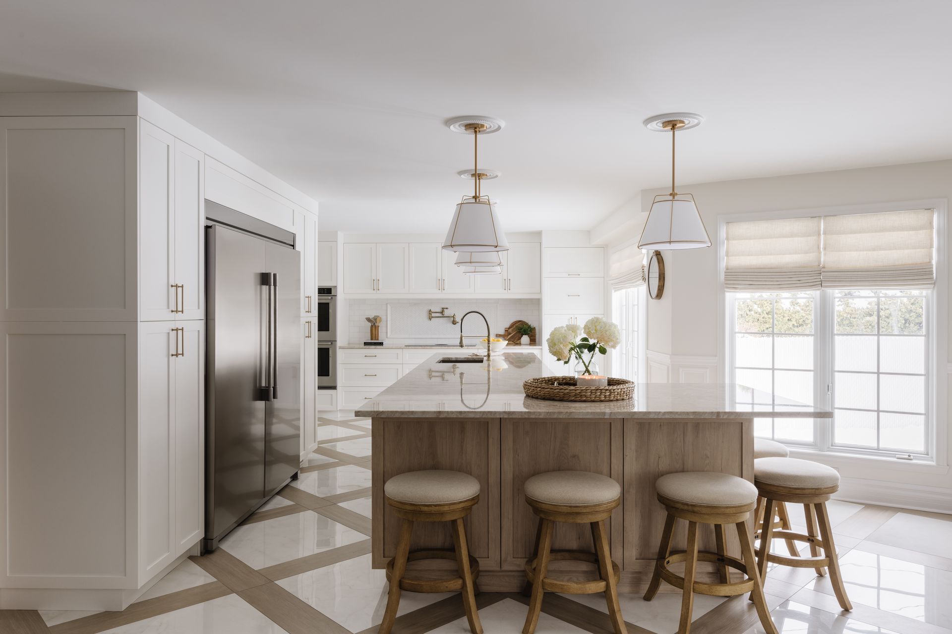 Bright white kitchen with wooden island, stainless steel fridge, and pendant lights.