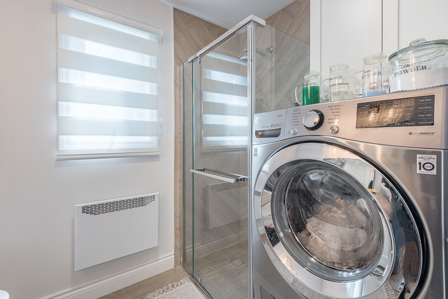 Laundry room with washing machine, shower, window with blinds.