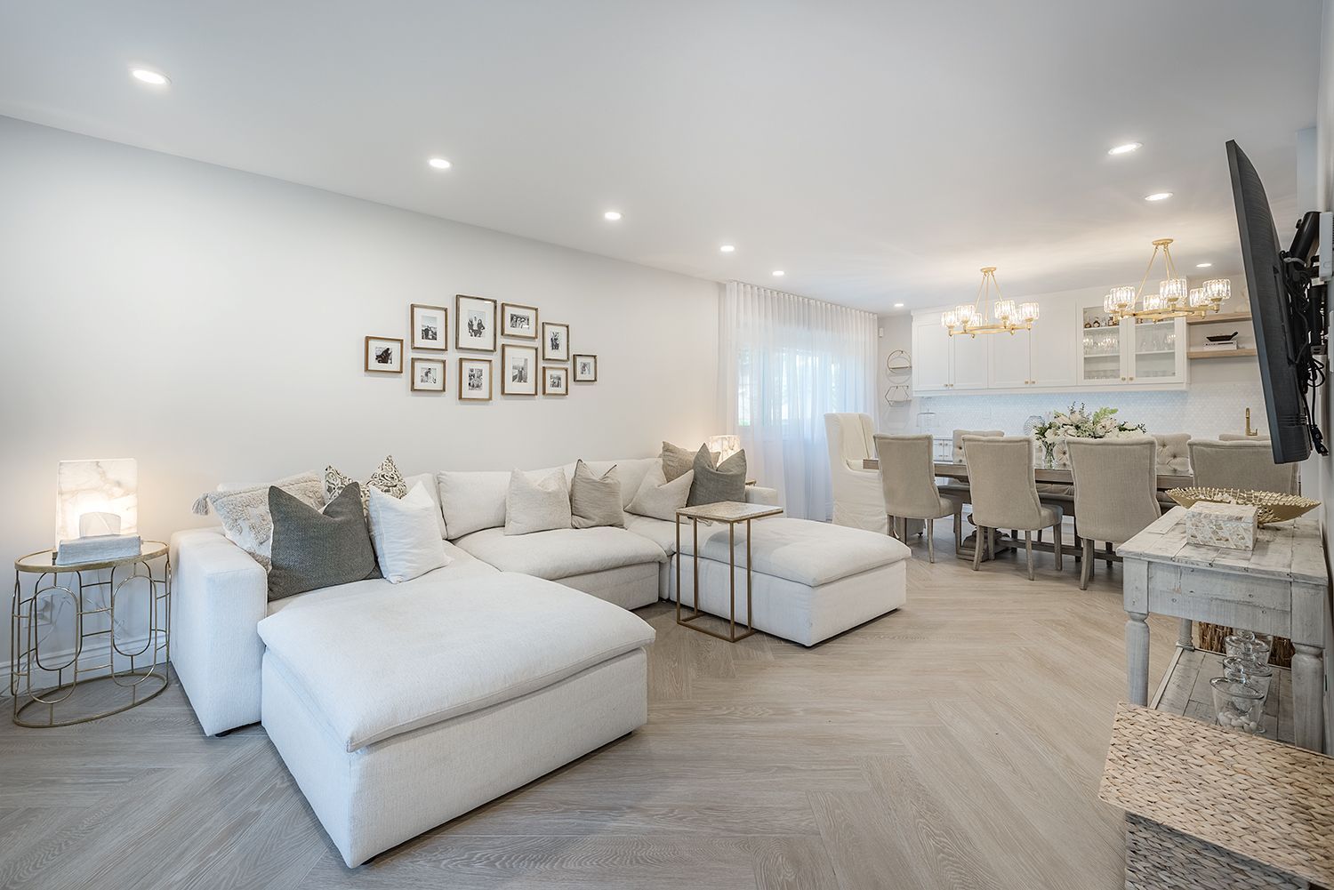 Bright, modern living space with white sectional, dining table, and kitchen area.