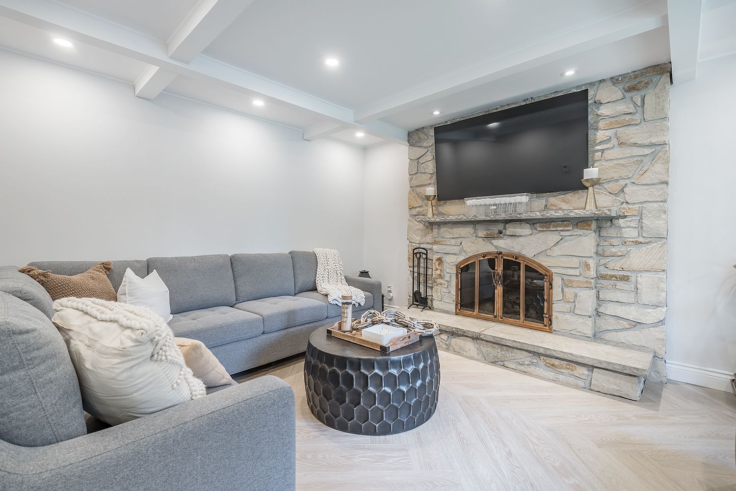 Gray living room with a stone fireplace, gray sofa, and a black coffee table.