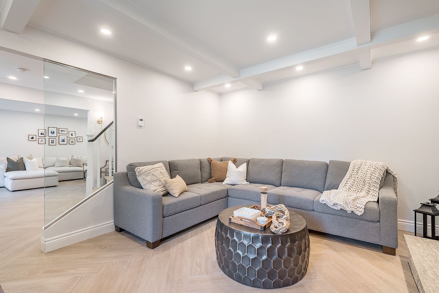 Gray sectional sofa in a bright, modern living room with a coffee table and white walls.