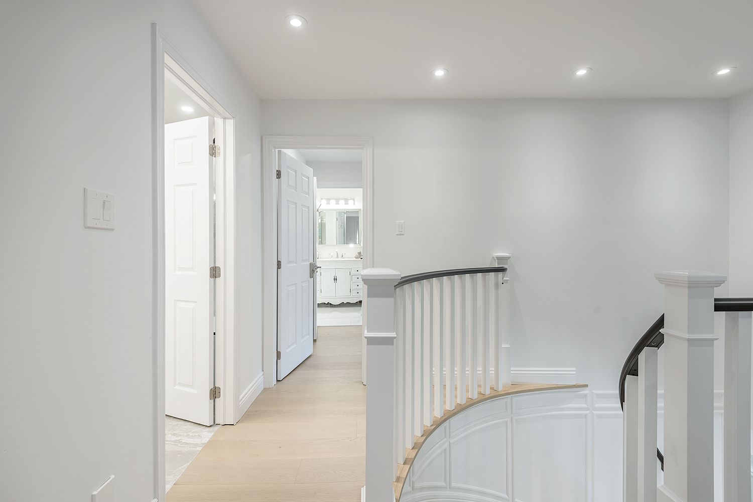 Hallway with doors, staircase, and white walls.