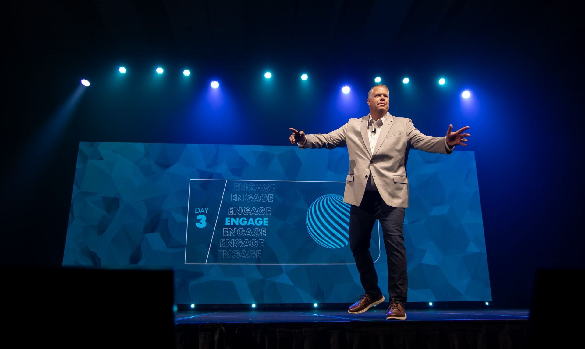 Conference presenter delivering a keynote from a professionally designed event stage.