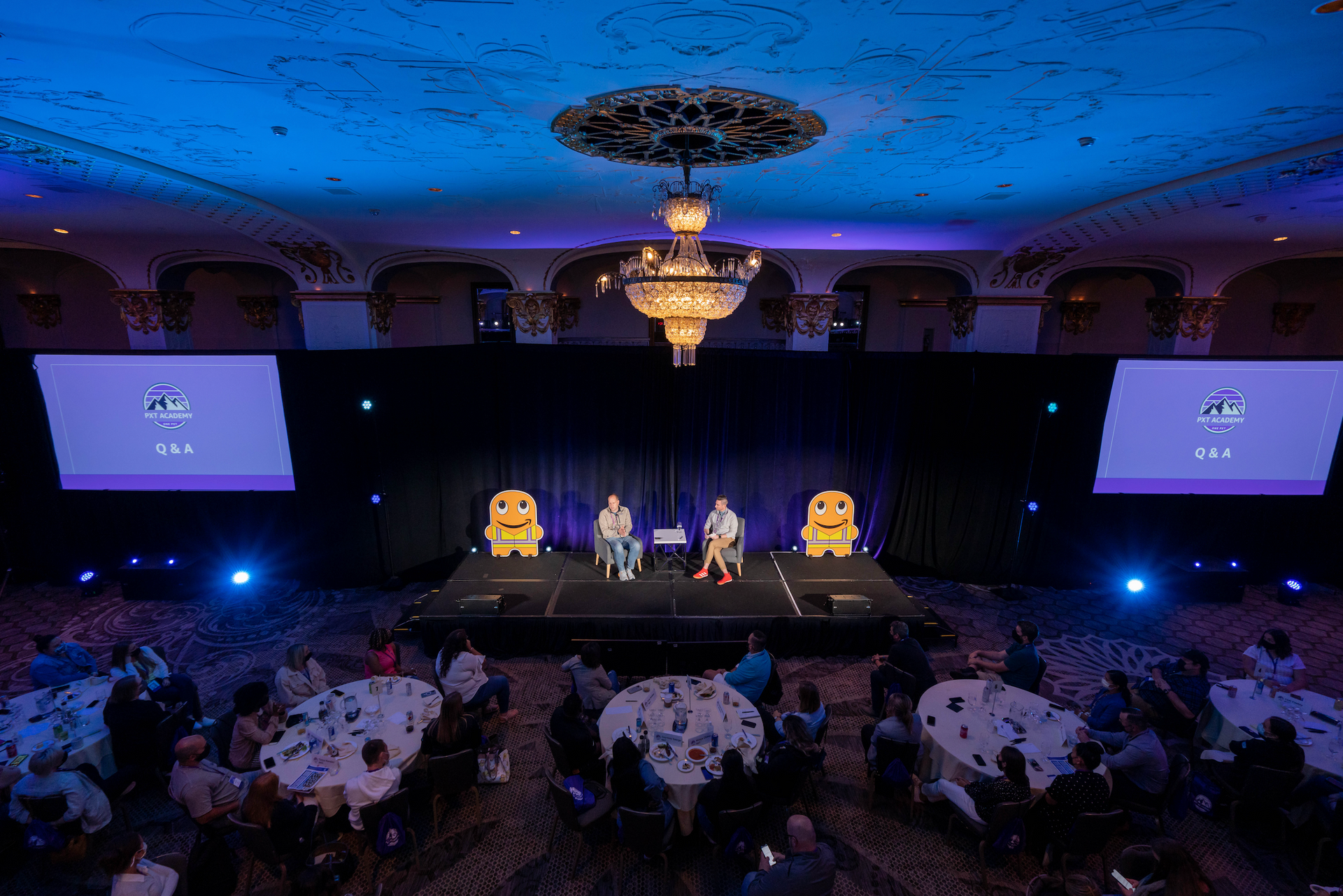 Corporate leadership panel on stage before attendees at a business conference.