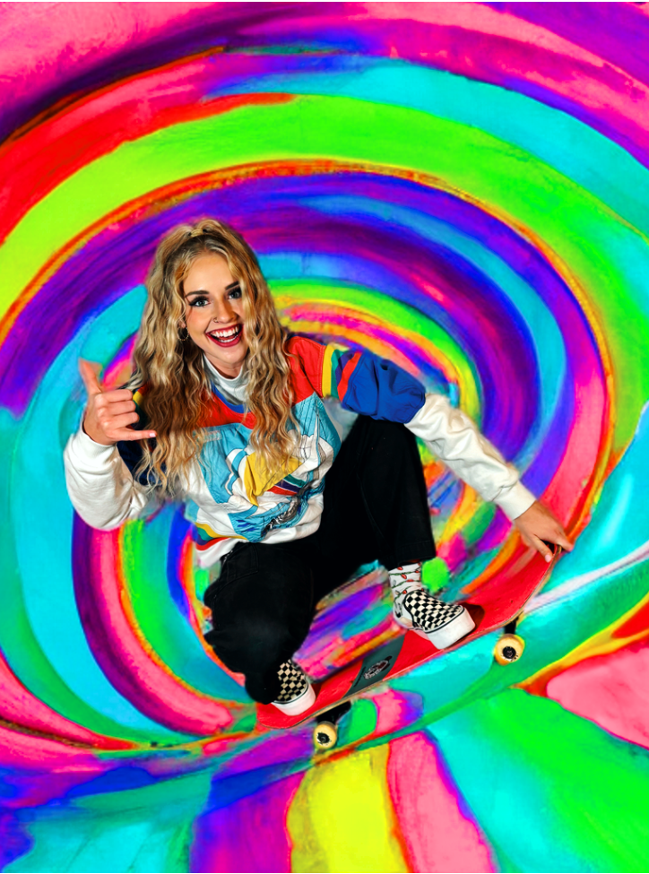 A woman is sitting on a skateboard in a colorful tunnel.