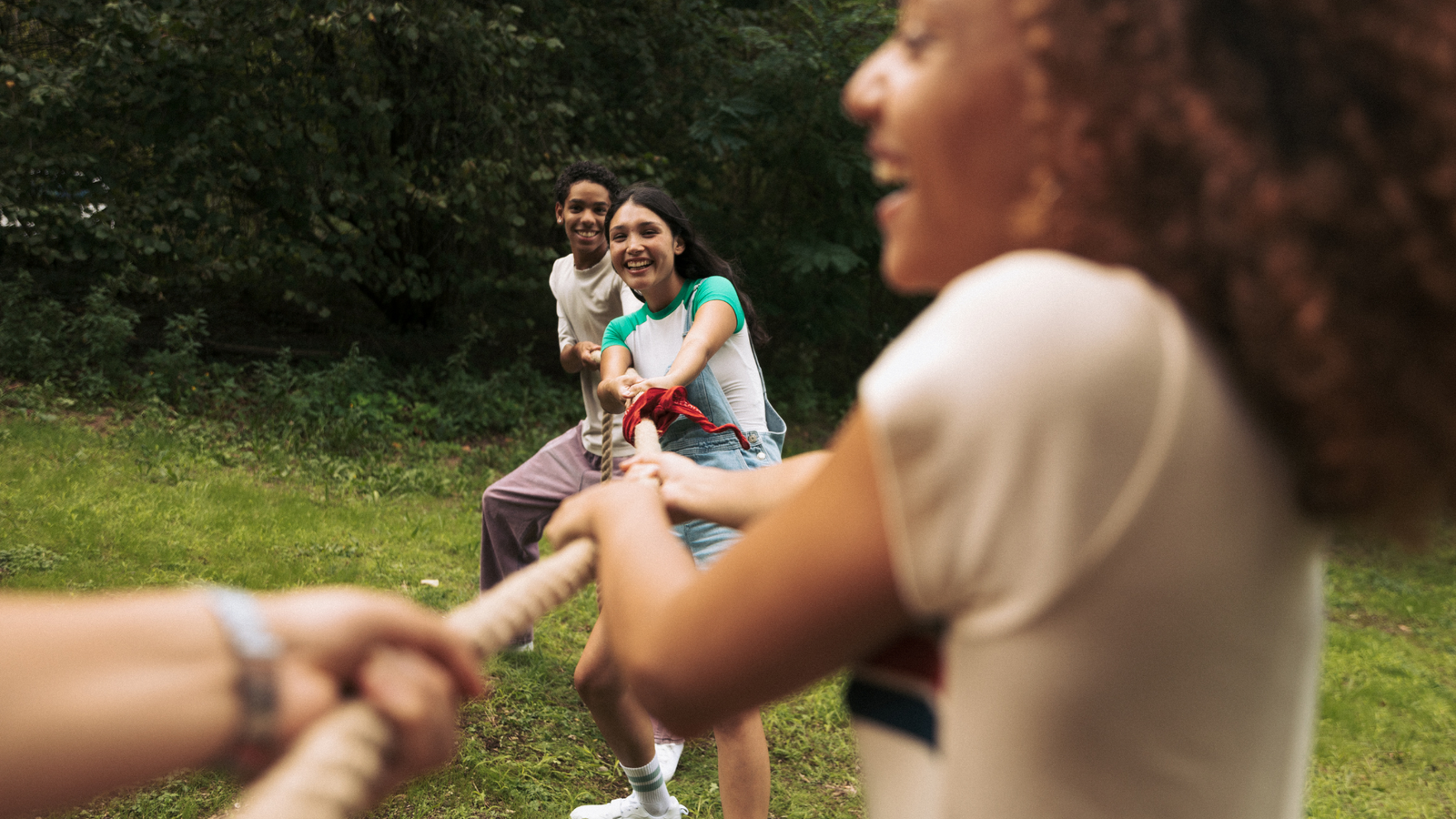 A group of teens playing tug of war & laughing