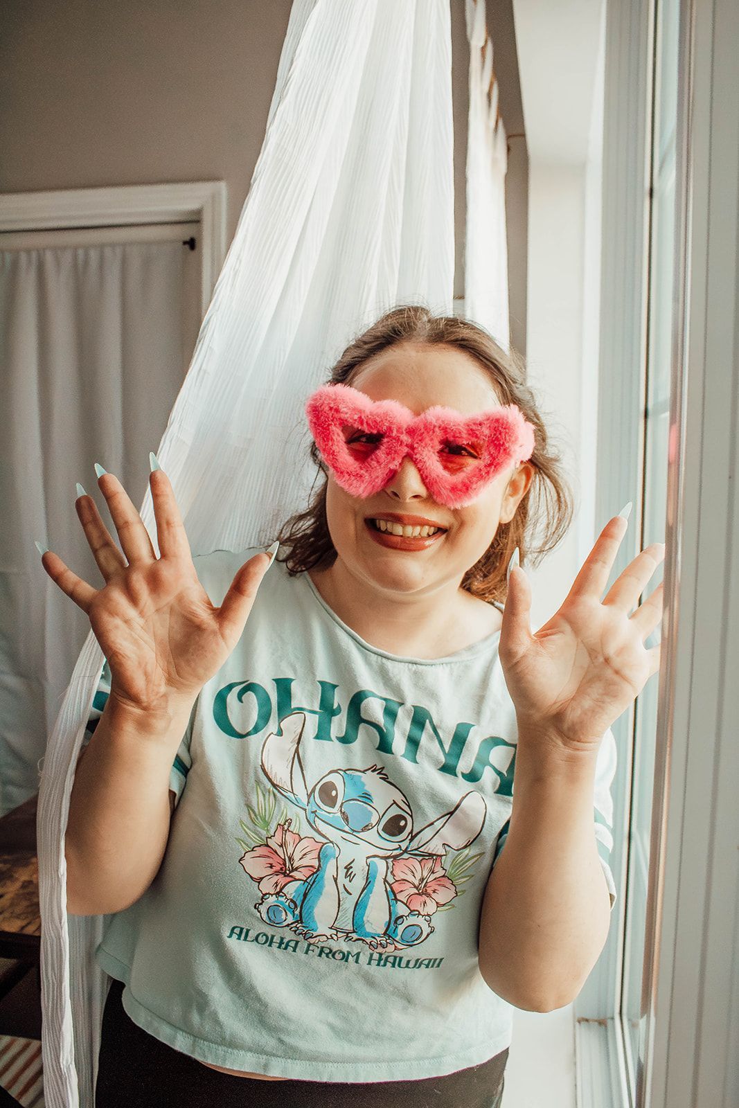 A woman is smiling while standing in the woods.