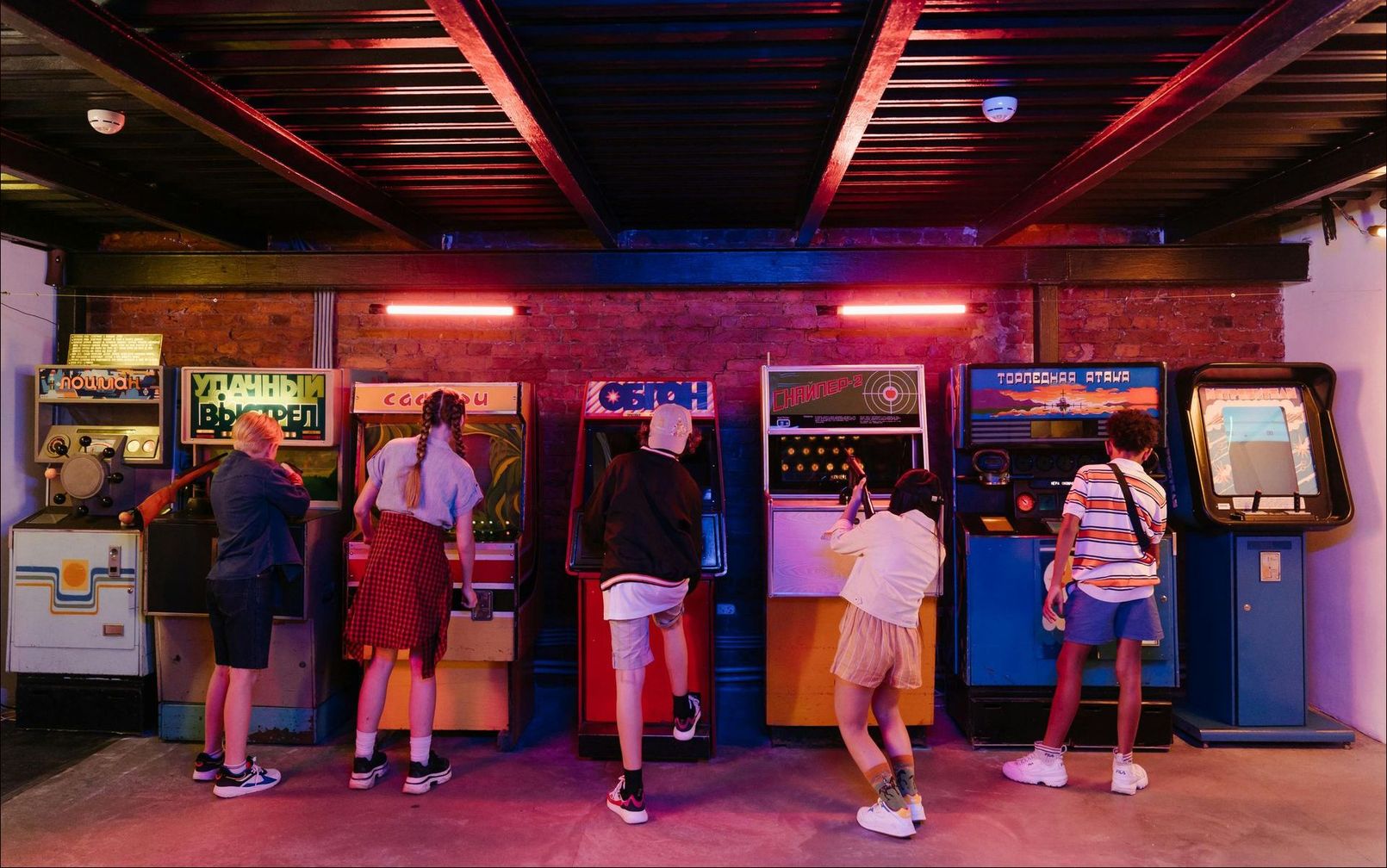 A group of people are playing video games in an arcade.