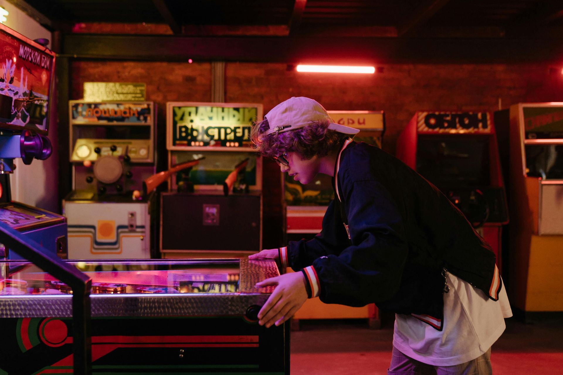 A man is playing a pinball game in an arcade.