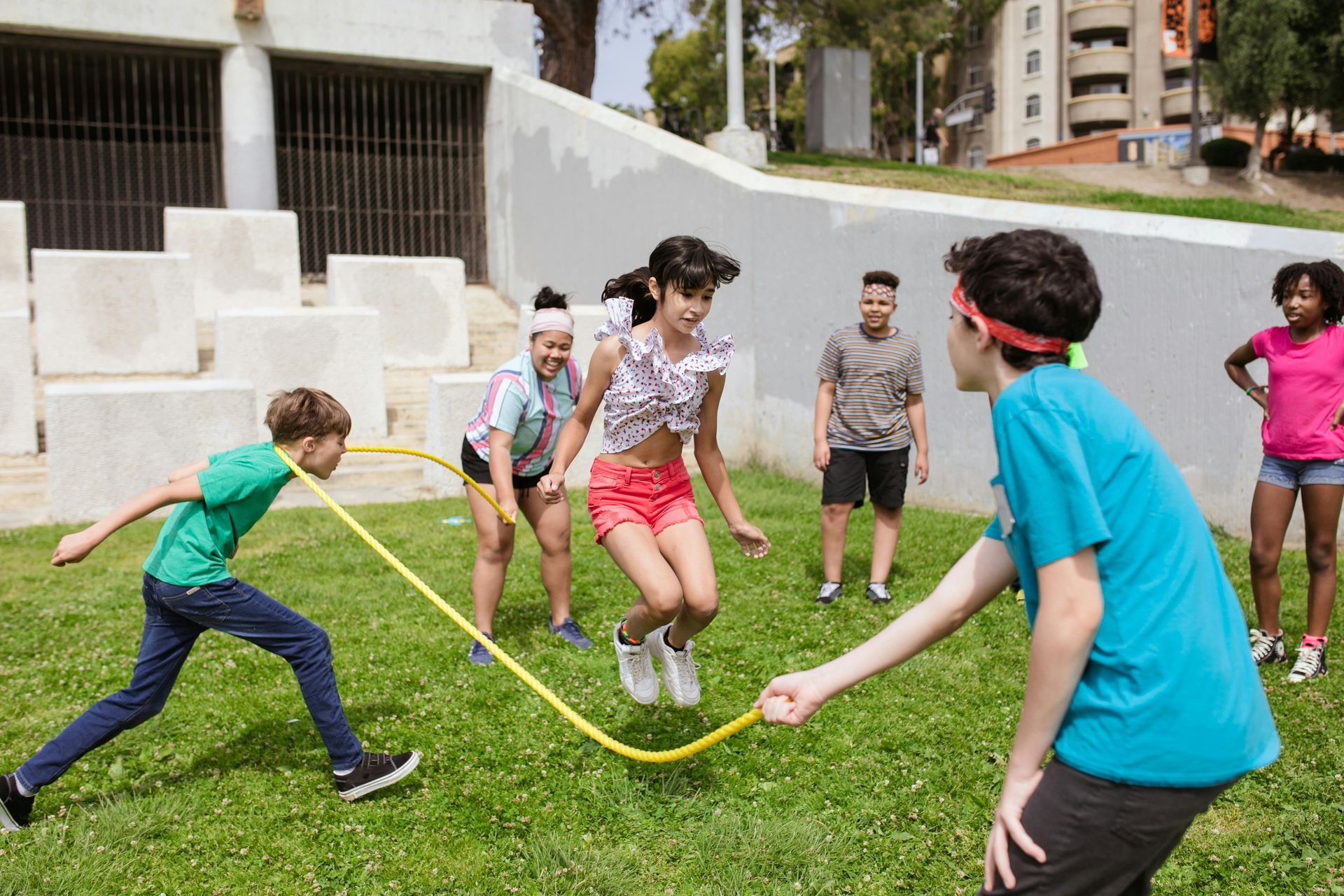 A group of children are playing with a jump rope in a park.