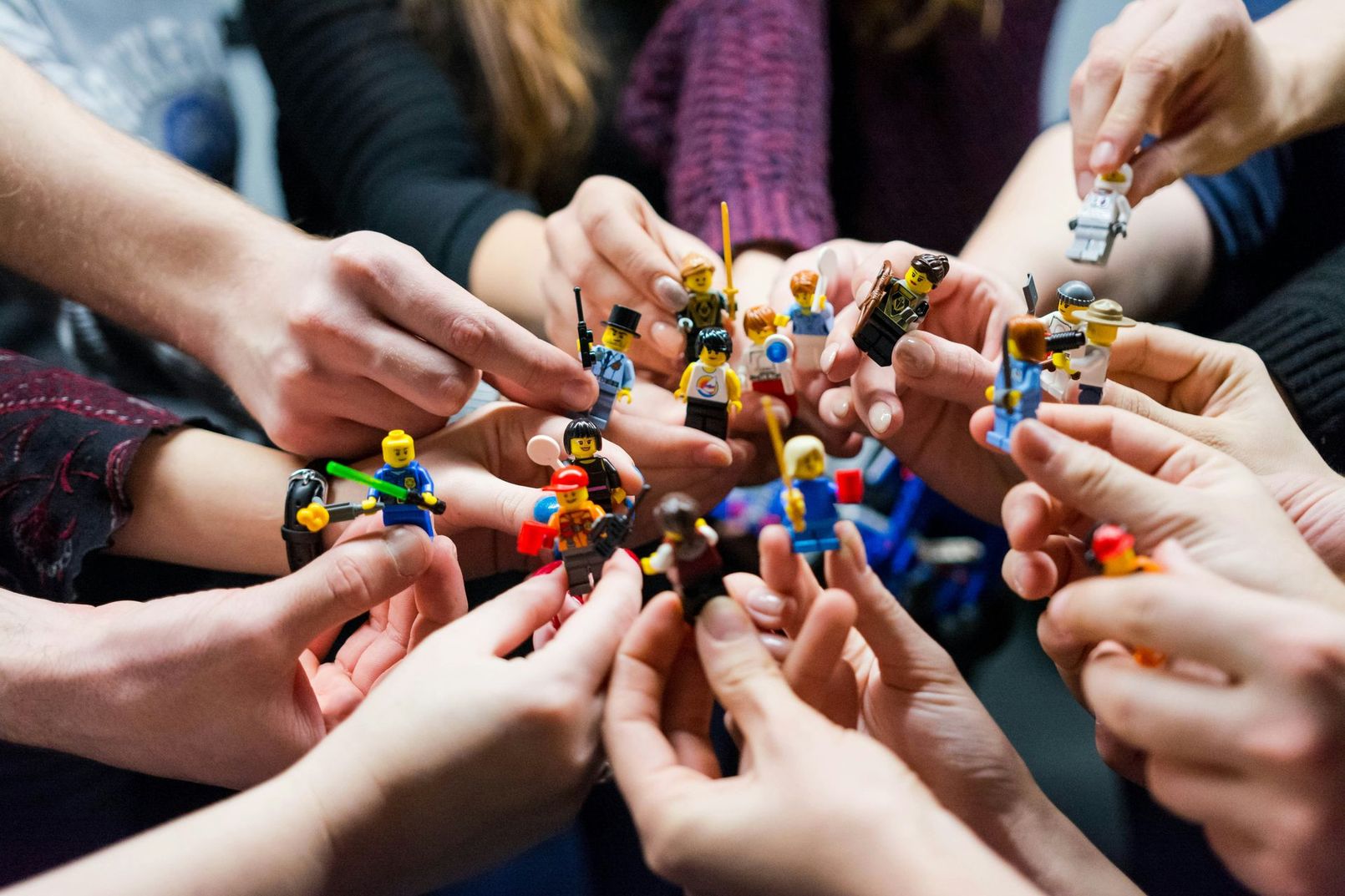A group of people are holding lego figures in their hands.