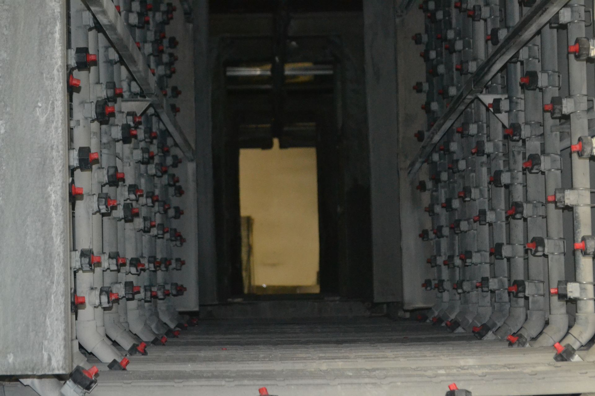 Un corridoio con un sacco di tubi e una porta sullo sfondo.