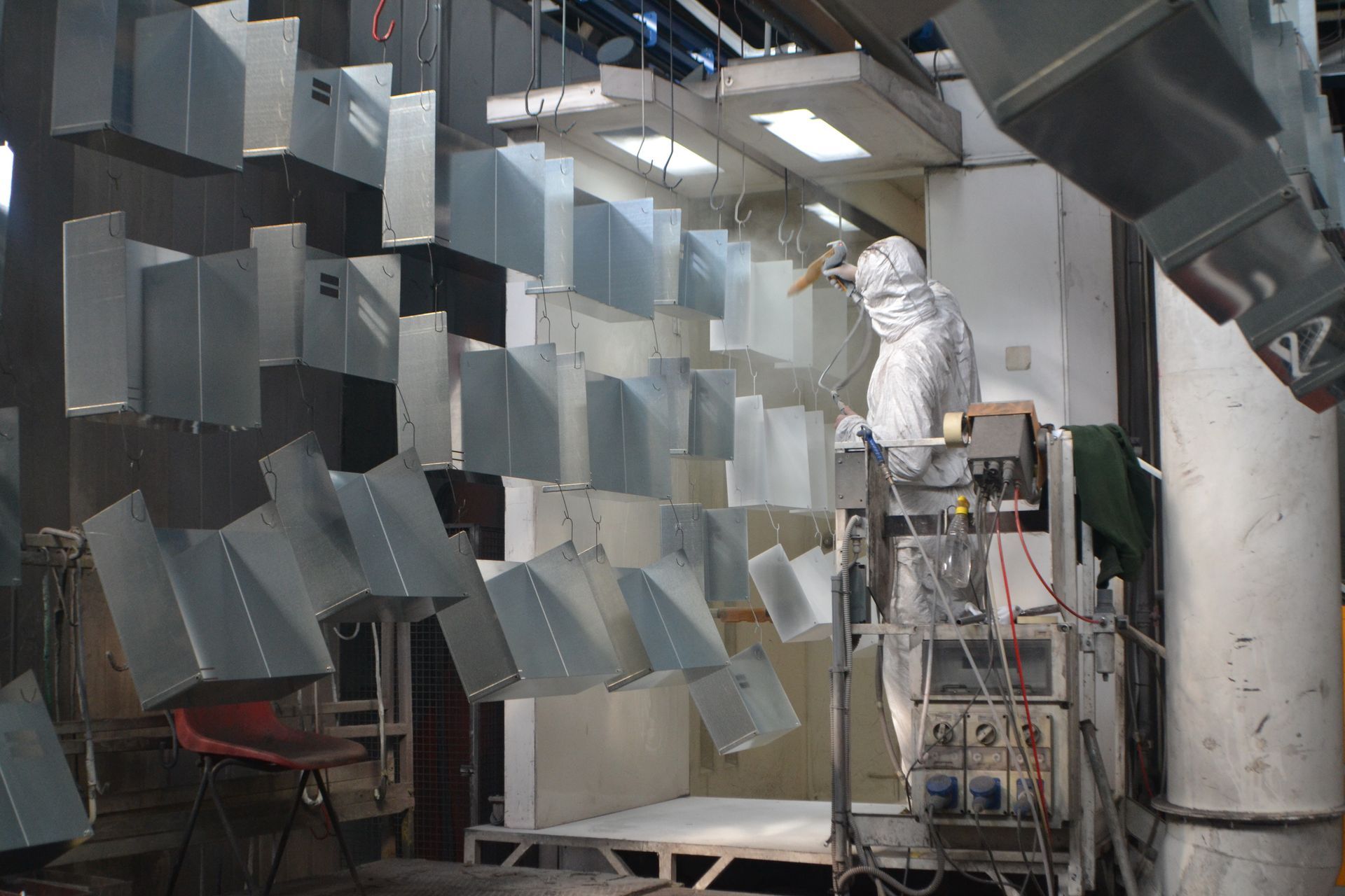 Un uomo con una tuta protettiva sta lavorando su una macchina in una fabbrica.