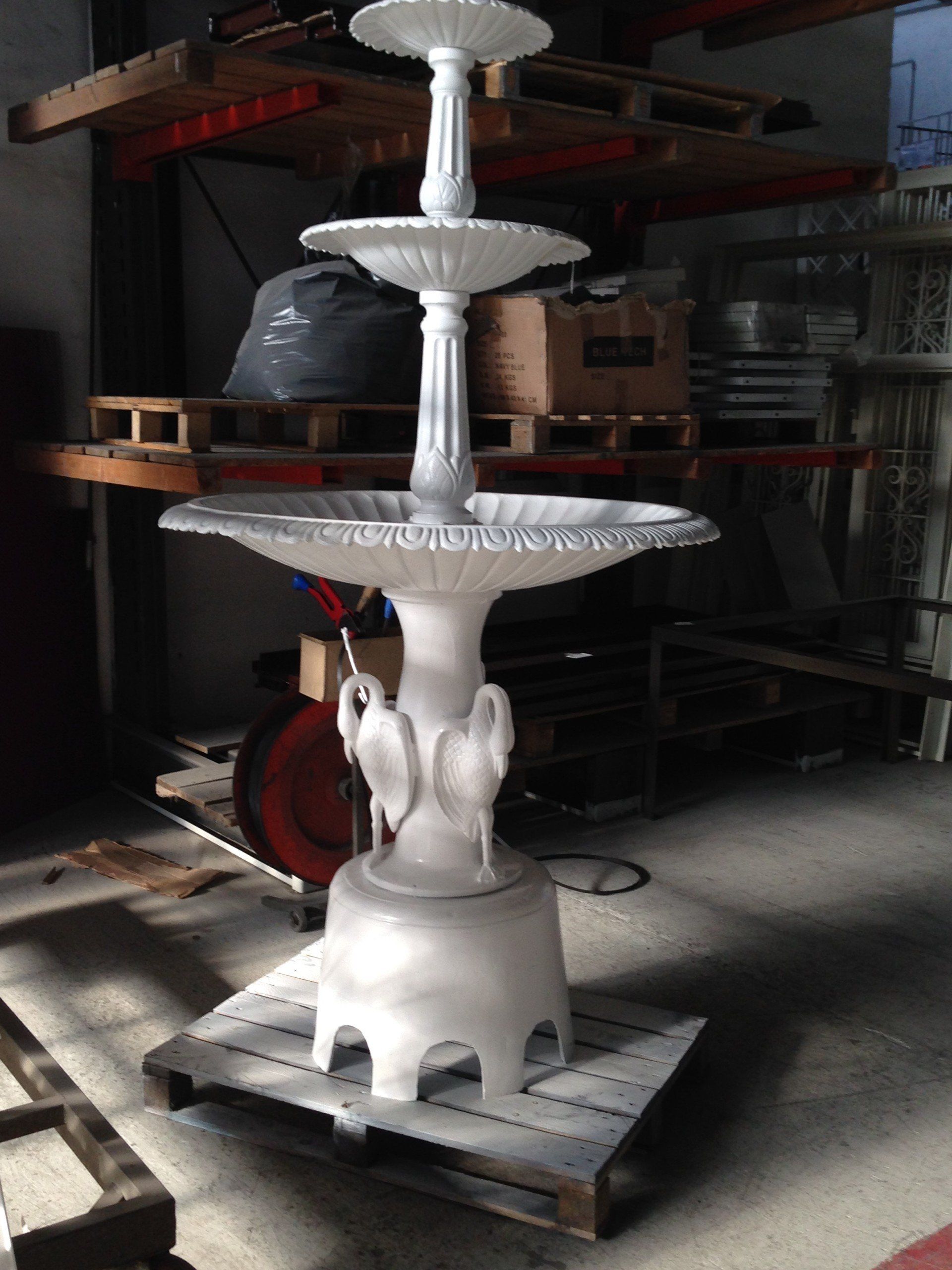 Una fontana bianca è appoggiata su un pallet di legno in un magazzino.