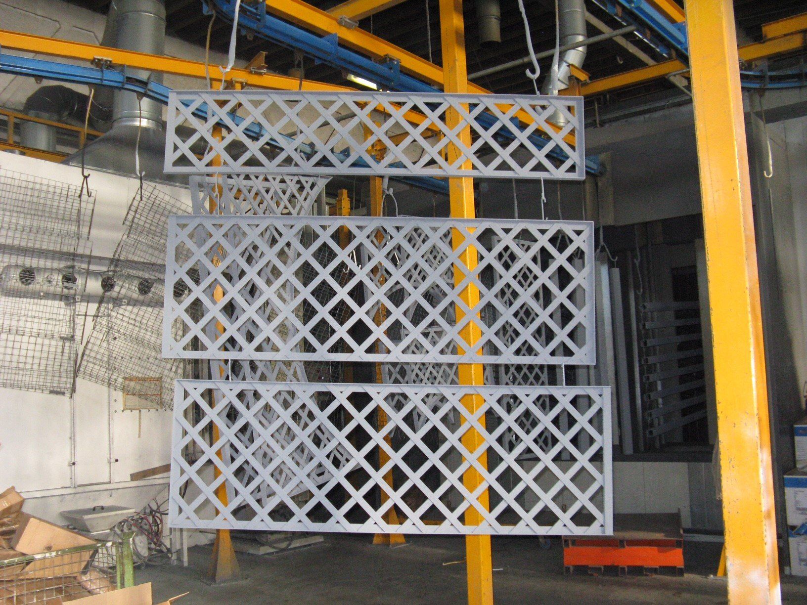 Una fila di recinzioni metalliche appese a un nastro trasportatore in una fabbrica