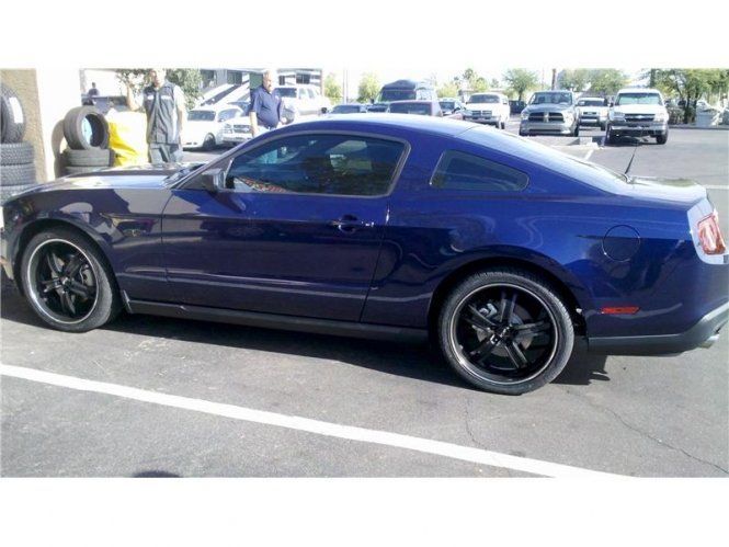 A blue mustang is parked in a parking lot