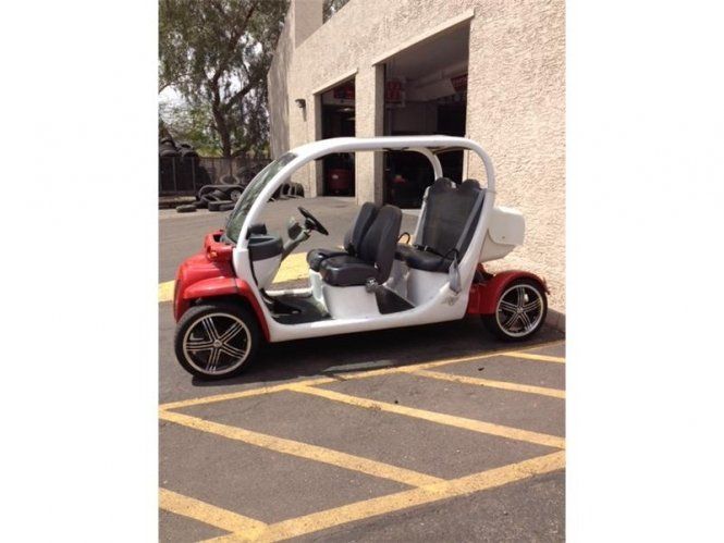 A red and white golf cart is parked in a parking lot