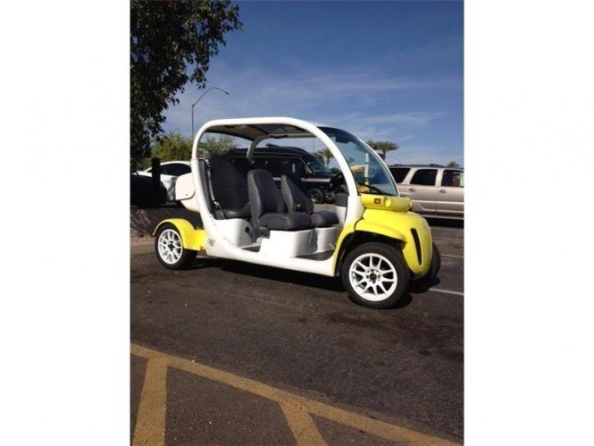 A yellow and white golf cart is parked in a parking lot