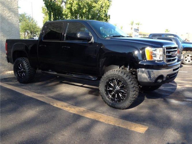 A black truck is parked in a parking lot.
