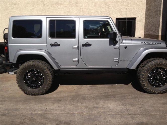 A silver jeep is parked in front of a building