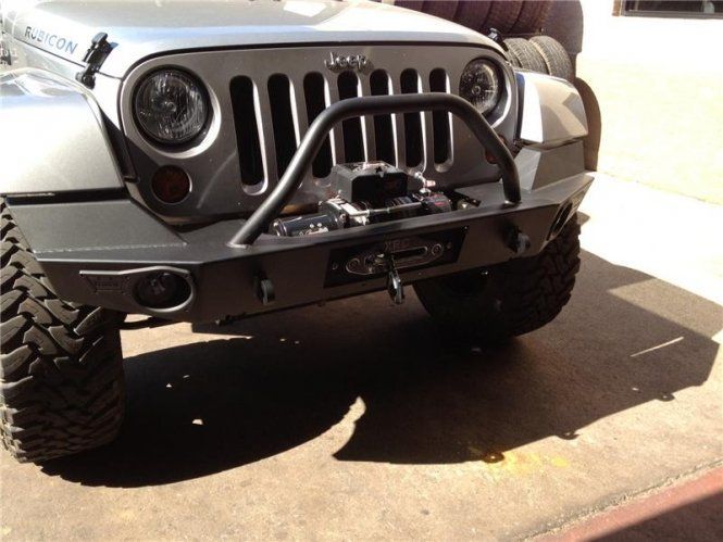 A silver jeep is parked on the side of the road